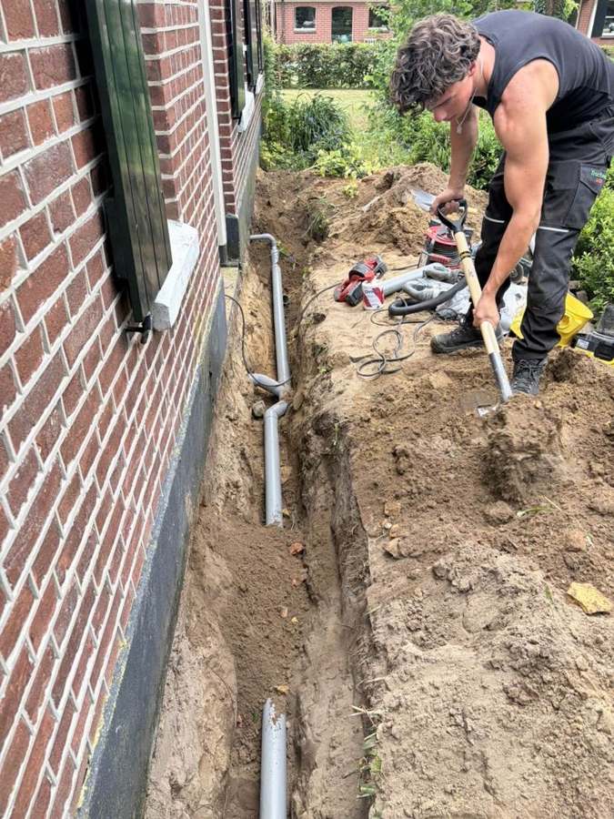 Nieuwe rioolleiding in een smalle sleuf langs de gevel in Dronten